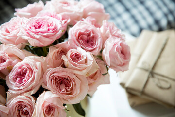 Rose White Pink O'hara. a bouquet of pink roses in round vase, wrapped gifts, books