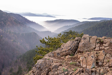 Rough rock on a mountain top with a view to hills that are peeking through clouds, Divcibare, Serbia