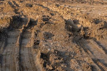 Big car wheel trace on road, puddle and mud