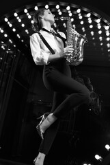 Fototapeta na wymiar Gorgeous brunette model woman in fashionable formal suit with saxophone