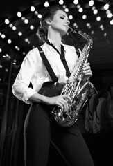 Obraz premium Gorgeous brunette model woman in fashionable formal suit with saxophone