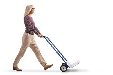 Full length profile shot of a young woman pushing an empty hand-truck