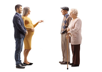 Full length profile shot of a young expecting couple talking to an elderly couple