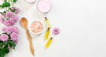 Home spa and wellness banner with Himalaya salt, essential oils, aromatic candles and beautiful flowers on white marble background with copy space for your design.