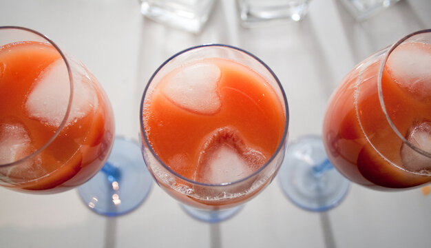 Three drinks with heart shaped ice cubes. Colorful fresh juice drinks in tall wine glasses for three girlfriends. Valentine's Day and friendship theme.