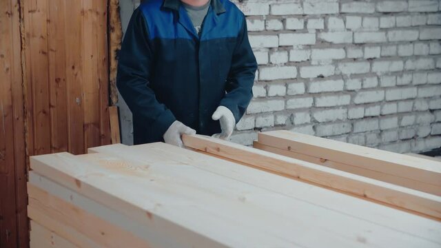 The carpenter arranges the boards neatly. A carpenter works with wooden planks.