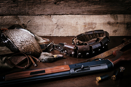 Hunting rifle, wild duck and belt with cartridges on old wooden. Still life in hunting still.