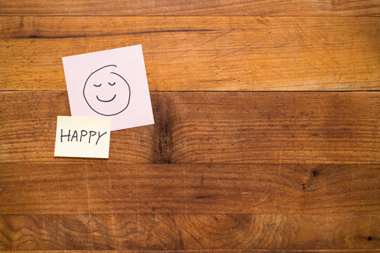 Happy face sticky note on wooden background. Human emotion and feelings concept. Text and copy space wallpaper