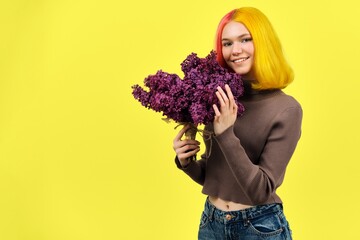 Teenager girl with dyed pink yellow hair holding lilac flowers in hands, copy space