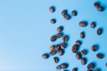 top view of coffee beans poured on a blue background, copy space