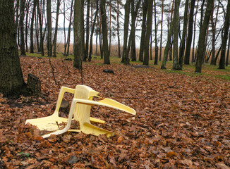 The plastic chair is in terrible shape and thrown in its natural environment. Ecology concept, plastic use, recycling.