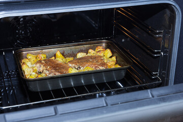 Two pork entrecotes with potatoes baked in the oven. Homemade food in the oven. Baked meat with vegetables. Pork meat in the oven