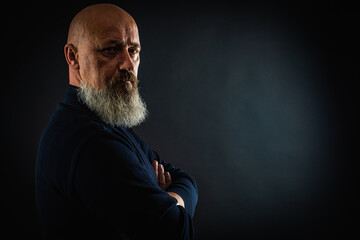 close up photo, portrait of a serious, thoughtful, bearded man on a dark background confident and dramatic looking straight. Concept of male portrait.  Low key 