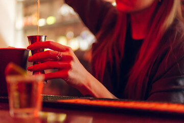 Bartender girl's hand holding jigger