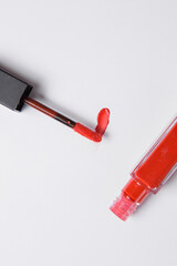 drop of red liquid lipstick smeared on a white background. Red lip gloss in a tube with an applicator on a white background
