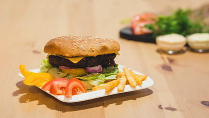 Beef Burger Served on White Plate with French Fries and Tomatoes