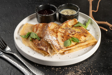 Crepe with berry sauce, mint and chia seeds. Classic hot breakfast. Pancakes made from eggs and flour. A traditional dish of Maslenitsa.