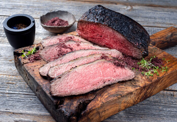 Traditioneller Roastbeef Aufschnitt mit Kräuter und Salz als close-up auf einem alten rustikalen Holz Board