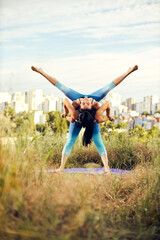 Fototapeta na wymiar Two strong women practicing acro yoga on a meadow.