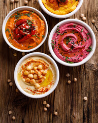 Different types of hummus on a wooden background top view