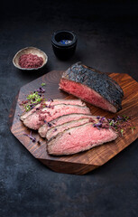 Modern style traditional Commonwealth Sunday roast with sliced cold cuts roast beef with herbs and salt served as close-up on a wooden design board