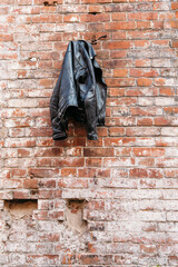 black leather jacket on the background of an old red brick wall of an abandoned building