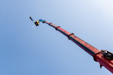 Skok na bungee z dźwigu na tle błękitnego nieba, widziany od dołu