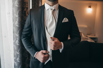 Shallow focus of an adult male wearing an elegant three-piece suit in a room
