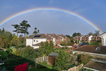 View of houses and gardens in southern Dublin with beautiful rainbow captured from a window during coronavirus lockdown, Dublin, Ireland. Wide angle view