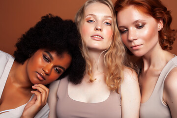 Obraz premium young pretty caucasian, afro, scandinavian woman posing cheerful together on brown background, lifestyle diverse nationality people concept