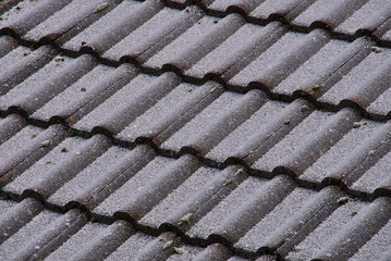 Irish style tile roof texture slightly covered with snow and frost on the last day of 2020, Dublin, Ireland. Diagonal pattern of roof tiling