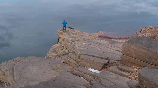 Senior male is hiking with his dog on a sandstone cliff - Horsetooth Reservoir in northern Colorado at foothills of Rocky Mountains in fall or winter scenery