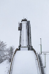 Straight view from under an empty ski jump tower covered with snow in winter - obrazy, fototapety, plakaty