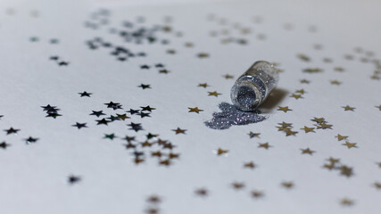 Transparent bottle with silver sparkles on a white background with silver stars. Magic backdrop with glitter. Minimalism concept
