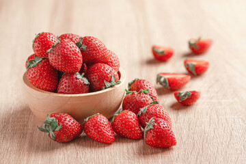 Strawberries in wooden bowl on wood background.