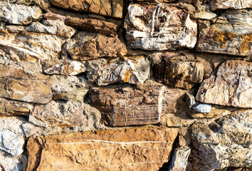 Fototapeta premium Wall made of irregular and natural stones along the beach of Baratti, province of Livorno, Tuscany, Italy, for texture and background