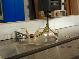 Close-up photography of protective goggles on the metal base of a edless saw in a carpenter...