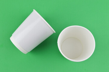 White cups isolated on a green background. 