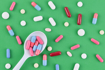 Colorful capsules and pills on green background. Top view. Medical concept. Copy space for text.