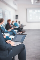 man using a laptop taking notes during a seminar presentation
