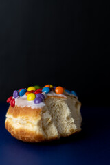 doughnut with icing and rainbow candy sweets on black background 