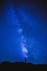 Fototapeta na wymiar Silhouette of girl / woman standing on the hill. Stargazing at Oahu island, Hawaii. Starry night sky, Milky Way galaxy astrophotography.