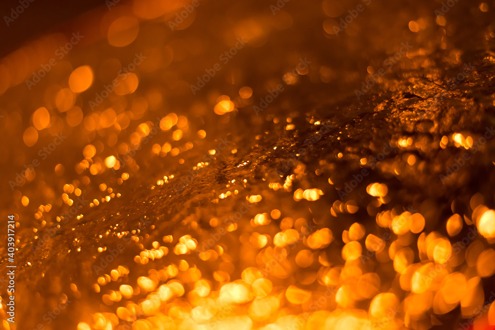 Sticker Closeup shot of a wet rocky surface with orange light bokeh