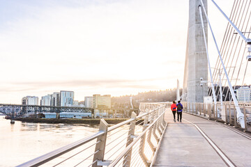 A couple walks over the Tilikum Crossing Bridge near sunset  in Portland, Oregon. - obrazy, fototapety, plakaty