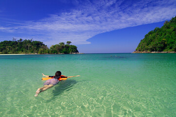 Summer beach vacation, woman swimming in calm sea at Koh Kam Tok Ranong, Thailand.