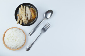 Flat lay view of chicken feet spicy soup with white rice, fork and spoon isolated on a white background. Famous Asian food.