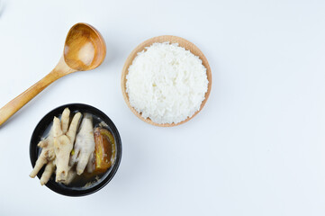 Fototapeta na wymiar Flat lay view of chicken feet spicy soup with white rice and spoon isolated on a white background. Famous Asian food.