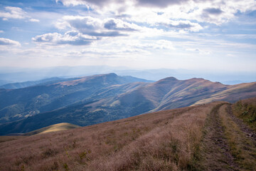 Fototapeta premium Beautiful mountain landscape of green and yellow meadows on Balkan Mountains in Serbia.Sunlit highlands and grasslands of Old mountain with distant peaks.Hiking trail for the highest peak Midzor 2169m