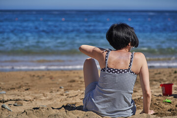 woman sitting on the beach looking at the sea Contemplation of the ocean.