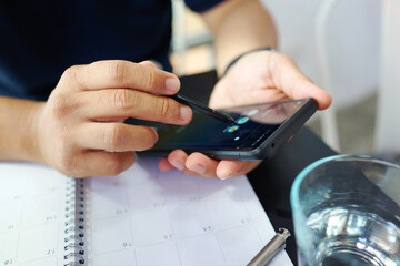 Businessman using mobile phone and planning agenda on planner. Schedule and planning.     